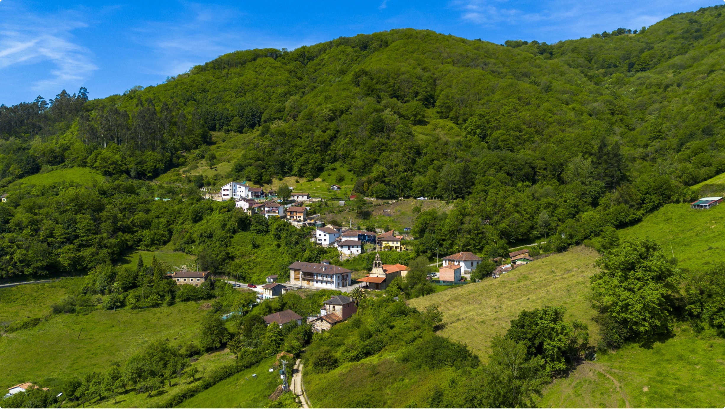 Vista panorámica de un pequeño pueblo rodeado de montañas y vegetación exuberante