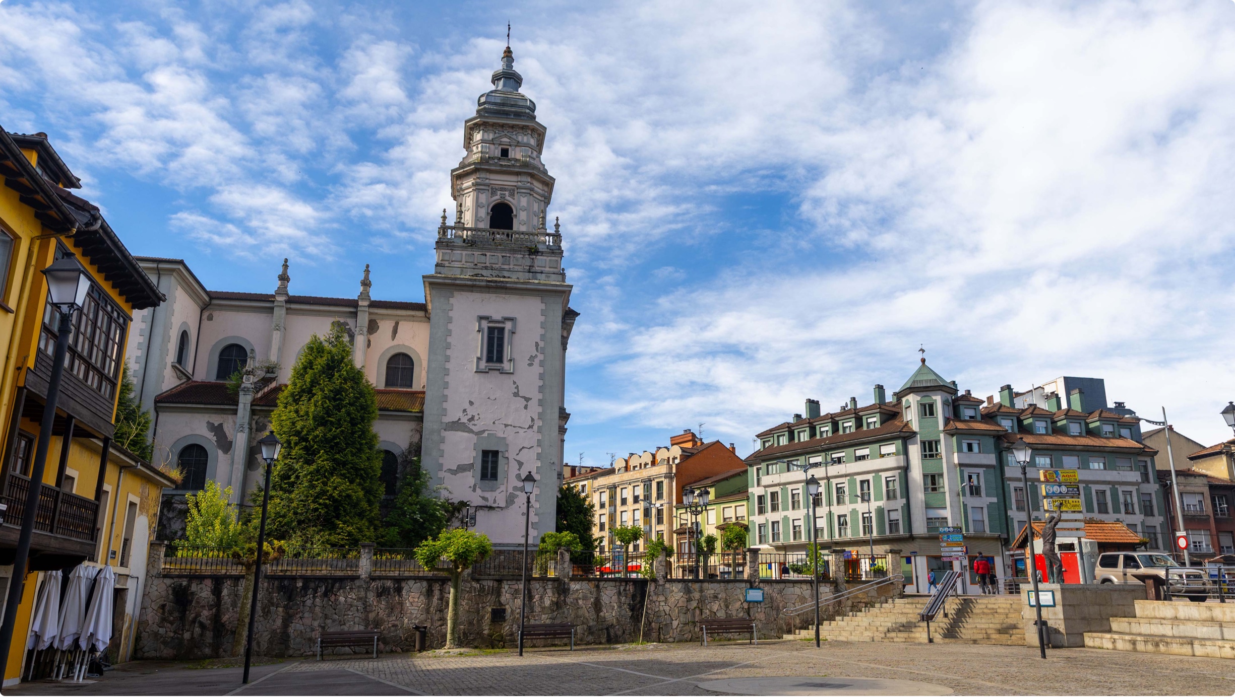 Plaza con edificios históricos y una torre de iglesia en un día soleado