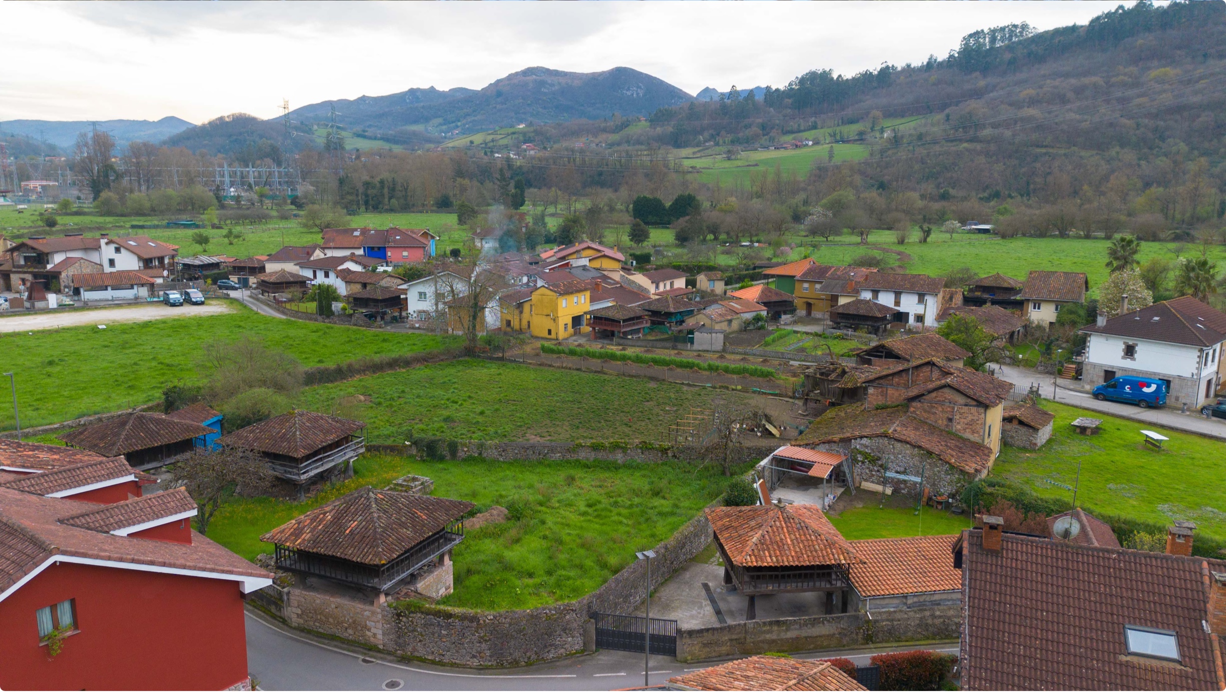 Vista panorámica de un pueblo rural con casas de tejados a dos aguas y campos verdes alrededor