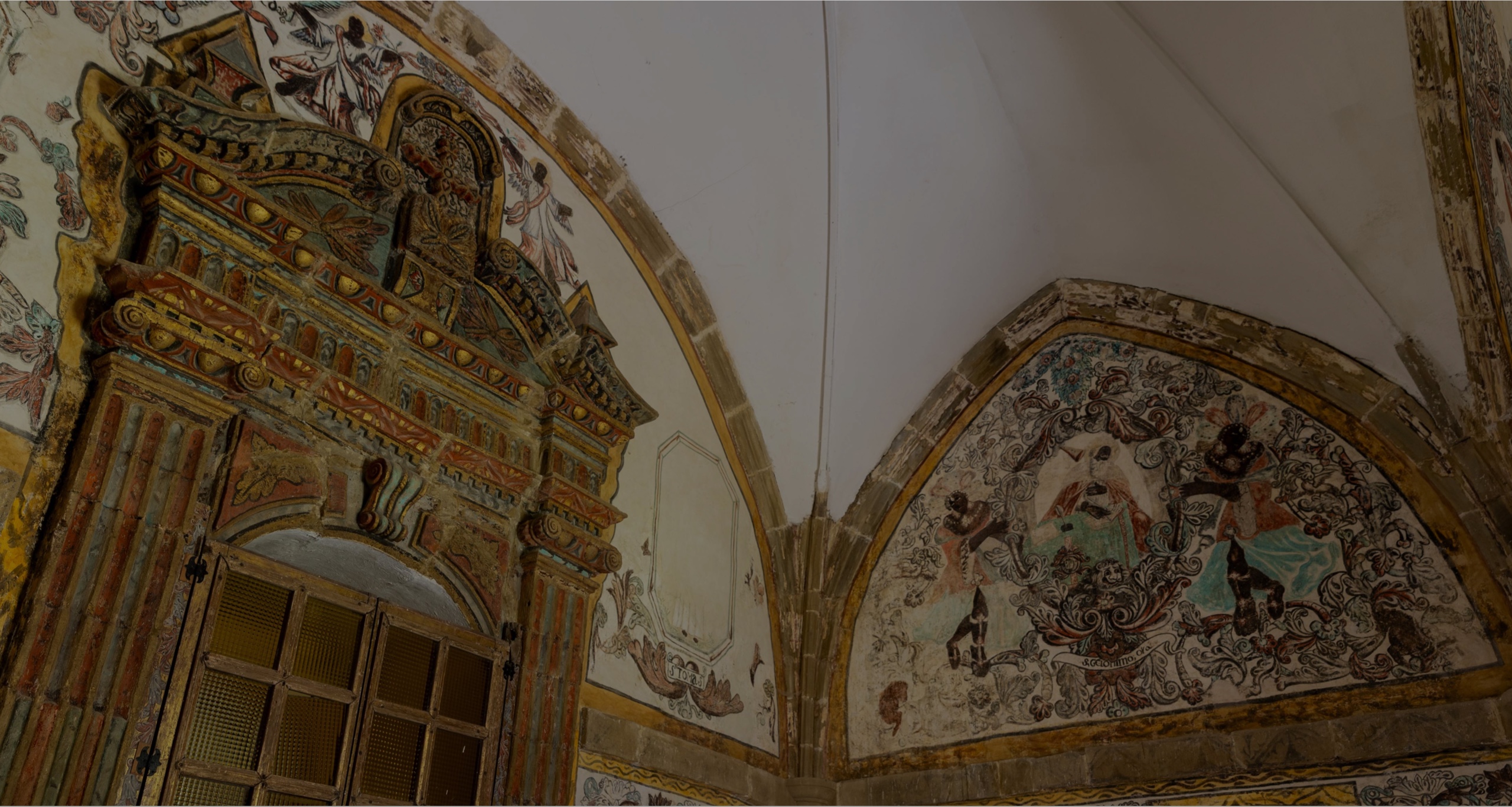 Detalle de una pared decorada con frescos y ornamentos en un edificio histórico