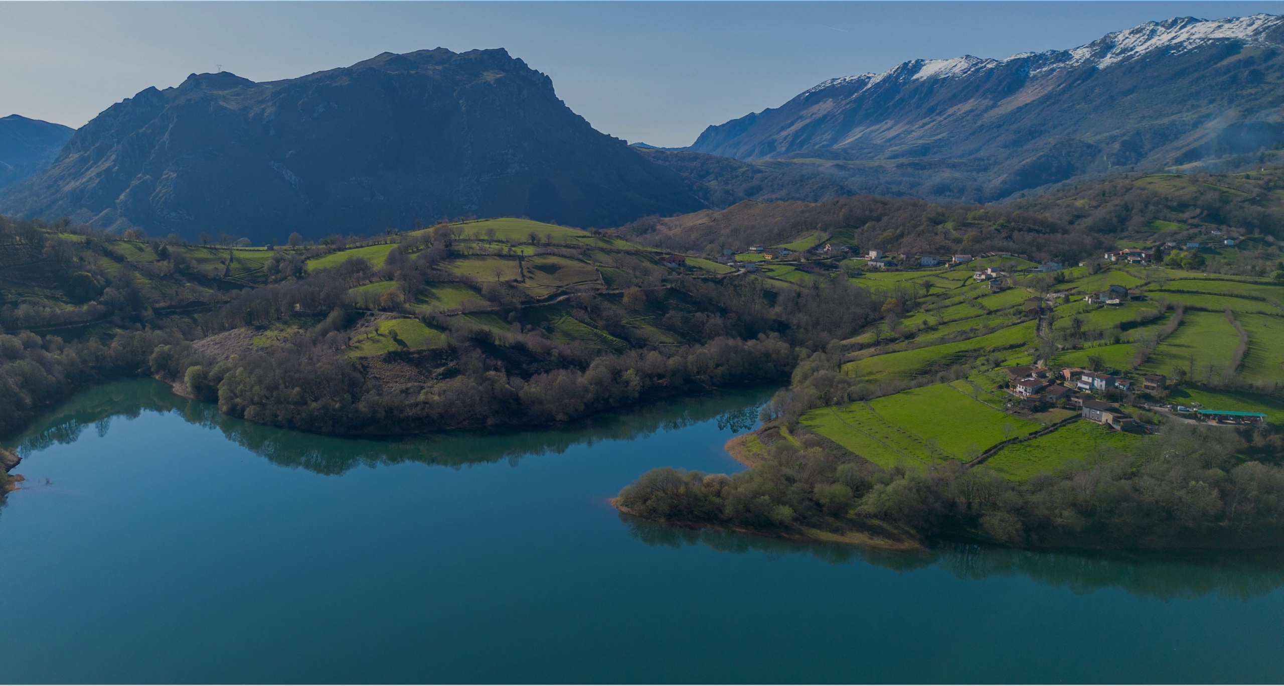 Vista panorámica de un paisaje montañoso con un lago y campos verdes