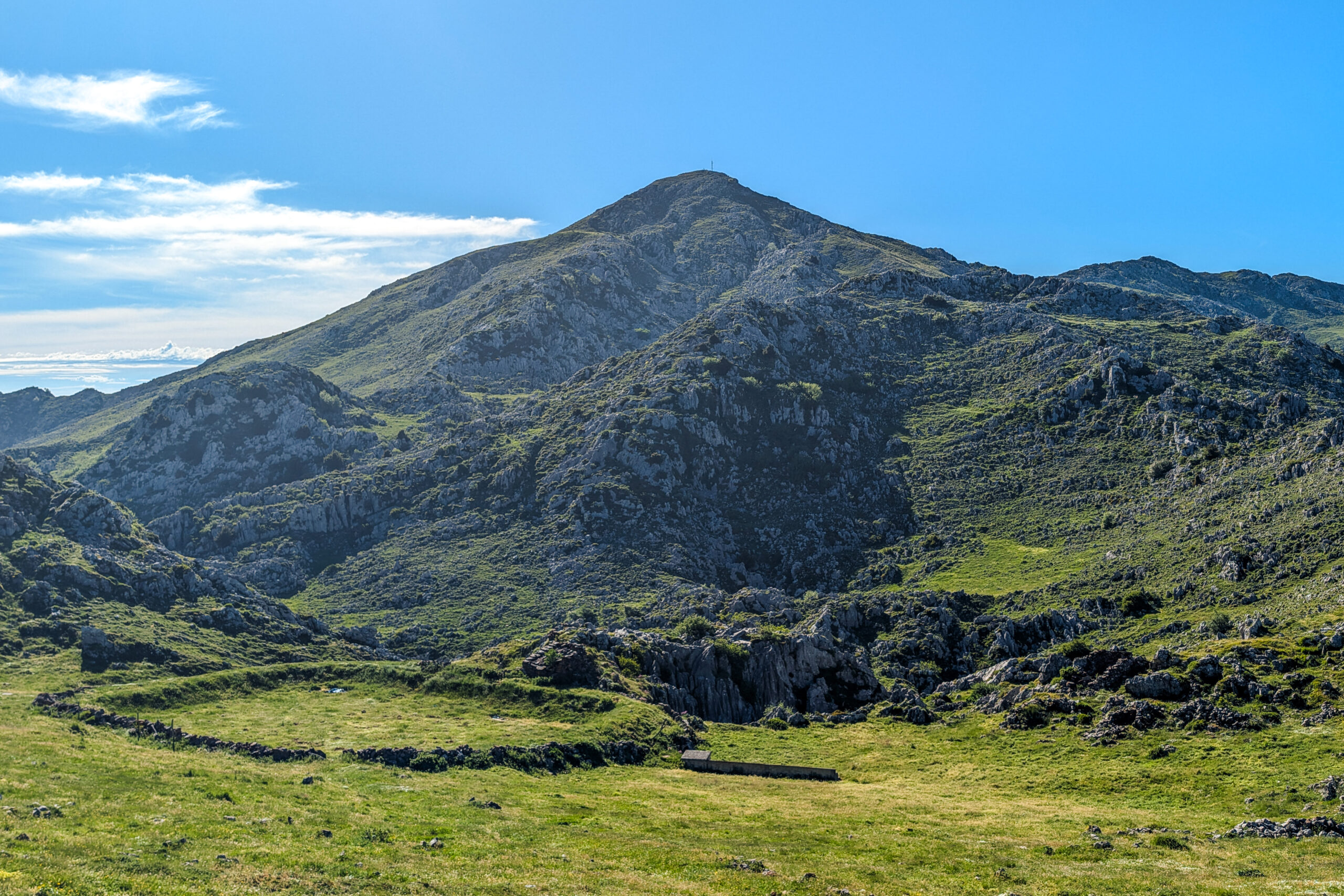 Montañas verdes bajo un cielo azul despejado con un pico prominente al fondo