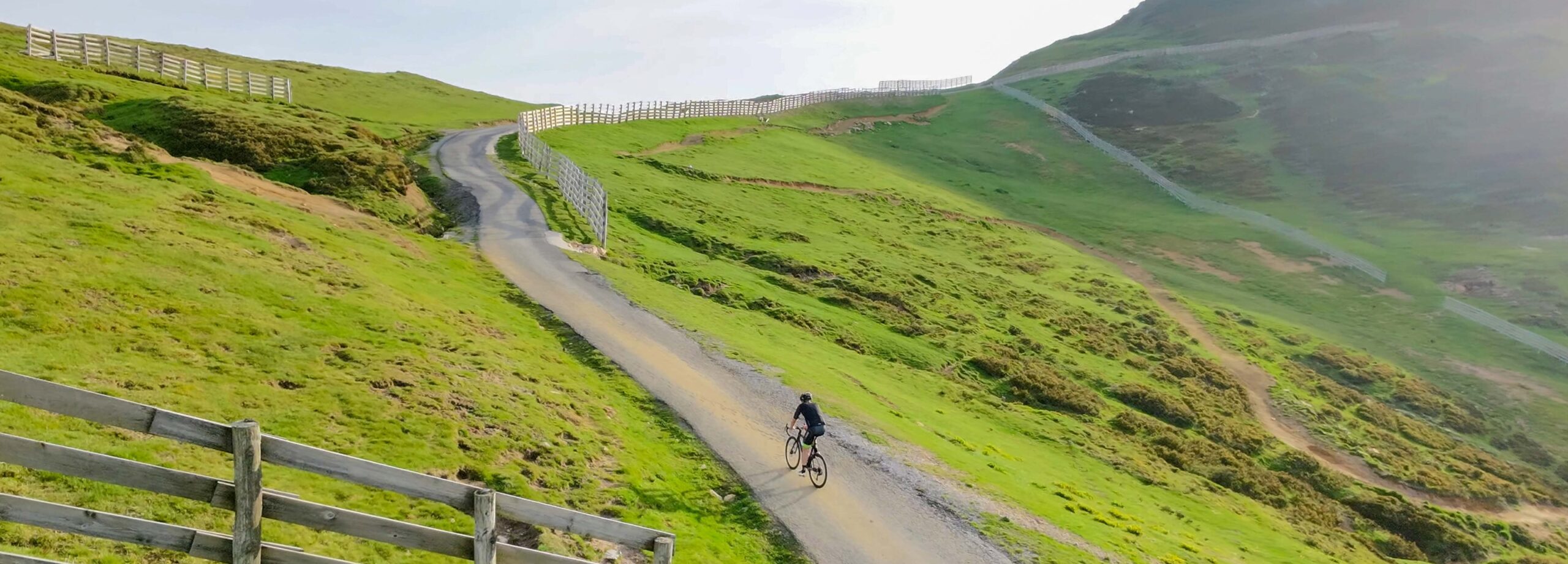 Ciclista recorriendo un camino en una colina verde con paisaje natural