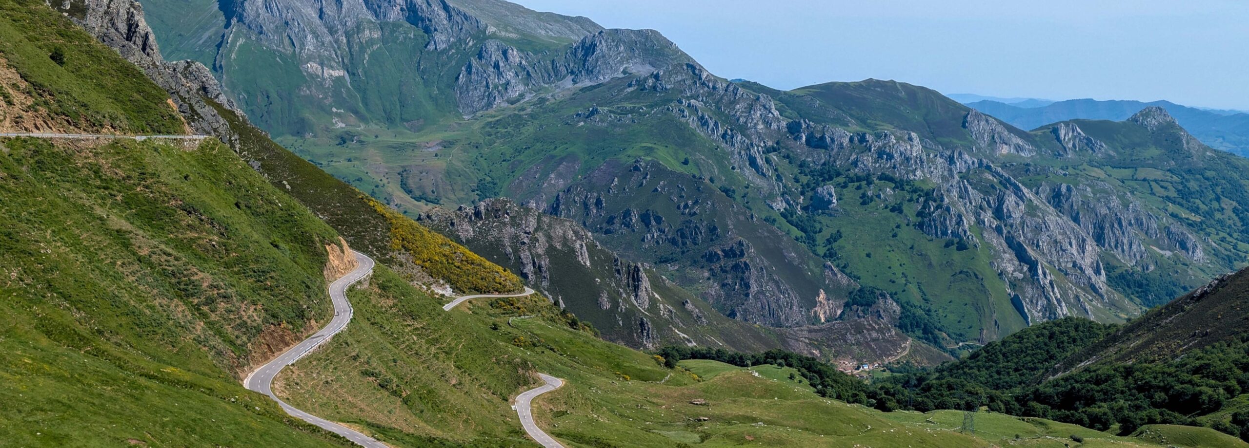Curvas de una carretera serpenteante en un paisaje montañoso verde y soleado