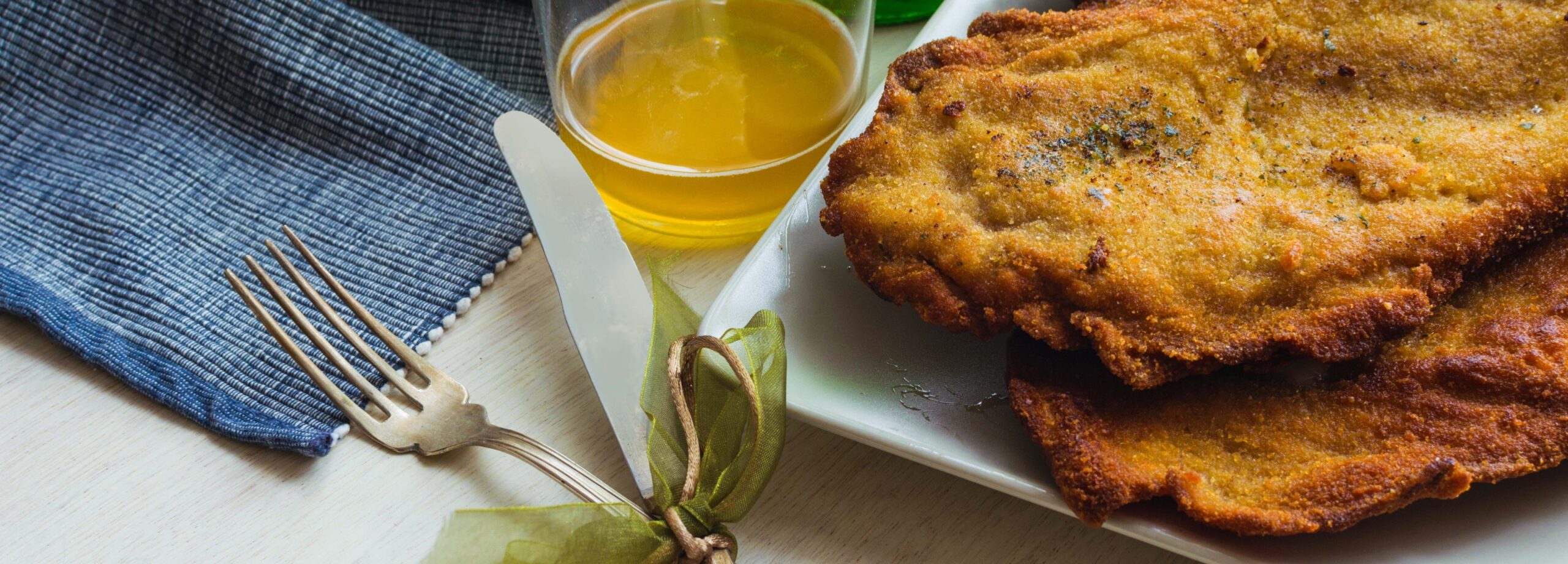 Plato con frituras doradas y un recipiente de salsa amarilla, acompañado de un tenedor y servilleta