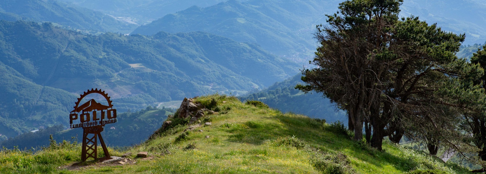 Paisaje montañoso con un letrero que dice "Pueblo" y un árbol en la ladera