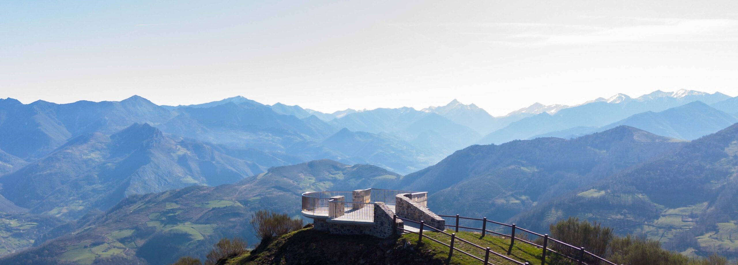 Vista panorámica de montañas con un mirador en la cima, bajo un cielo despejado