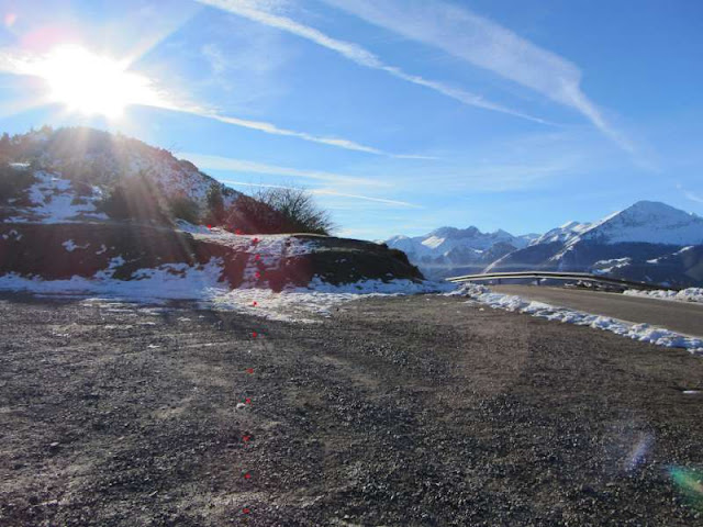 Paisaje montañoso con nieve, sol brillante y cielo despejado
