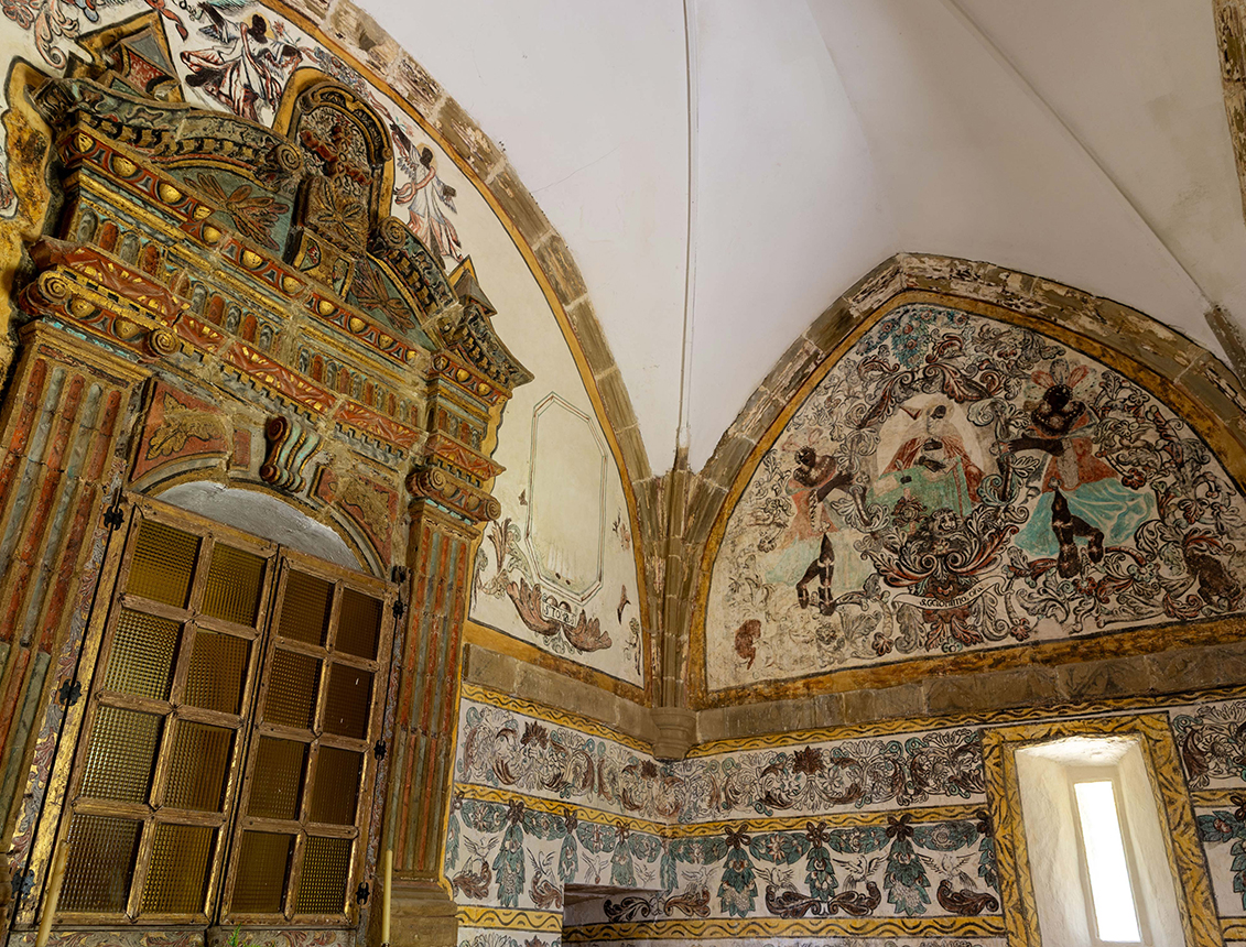 Interior de una habitación con paredes decoradas y un gran arco, destacando un elaborado marco de puerta