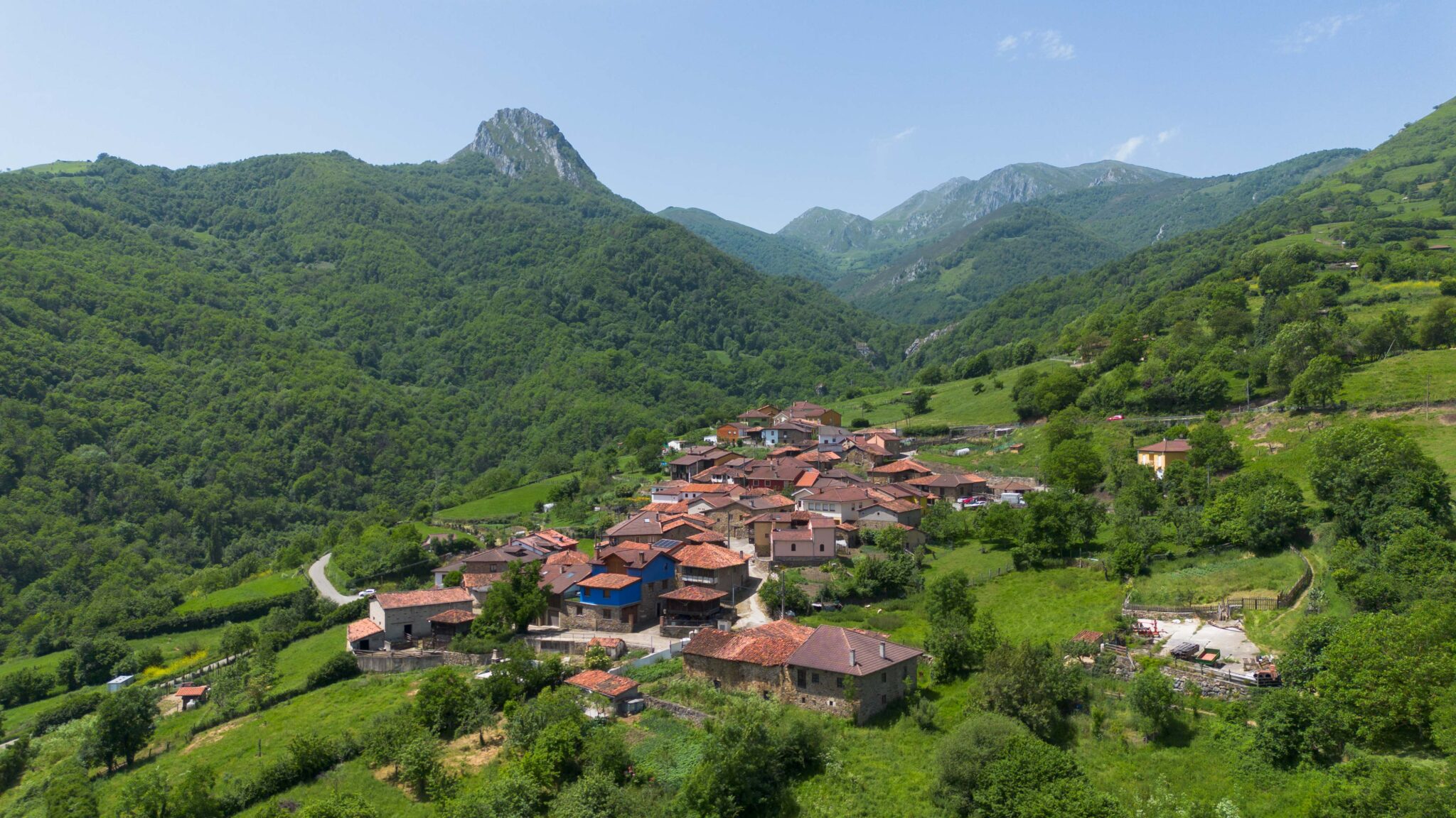 Vista panorámica de un pueblo rural rodeado de montañas y vegetación exuberante