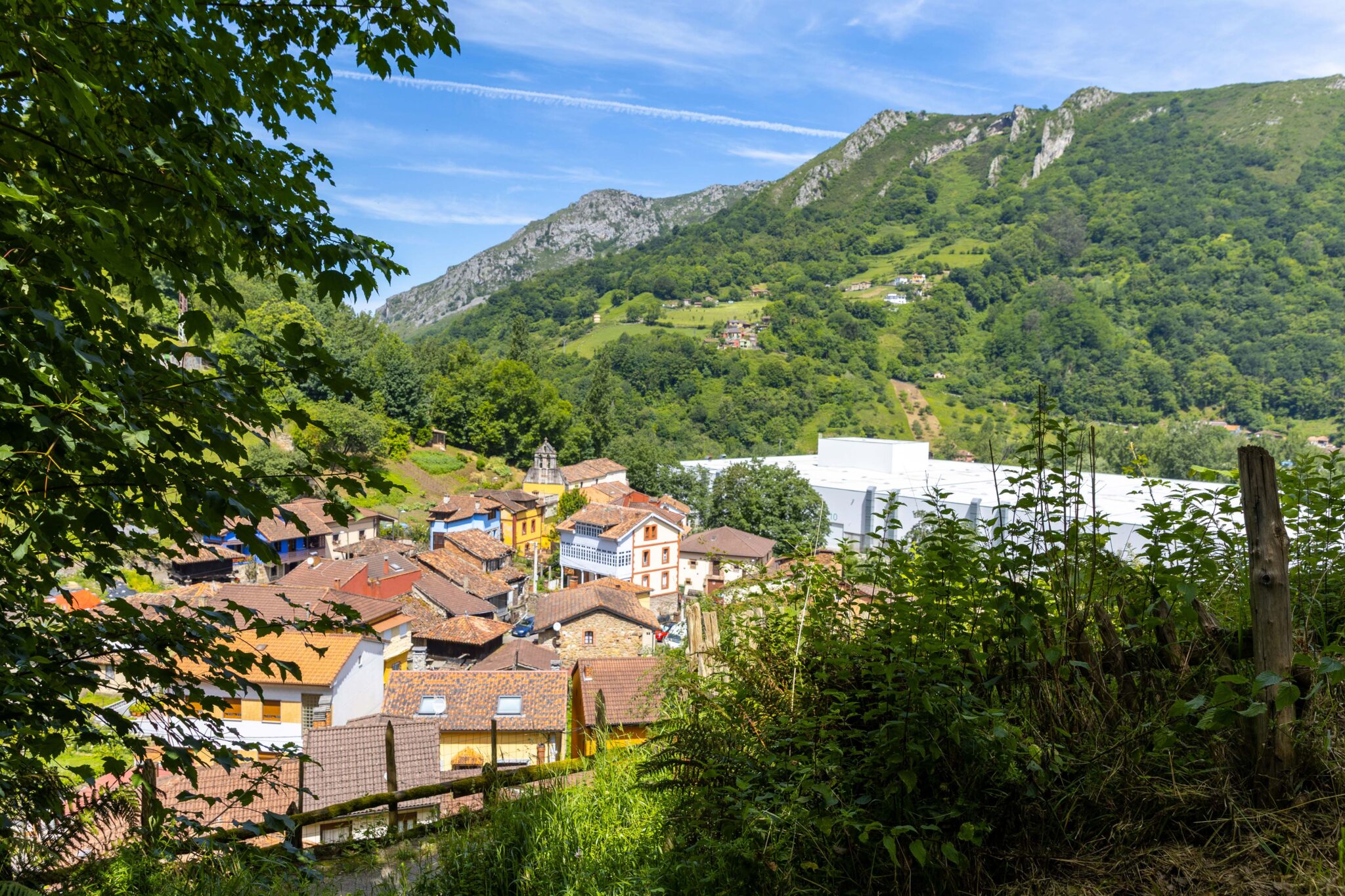 Vista panorámica de un pueblo con casas coloridas rodeado de montañas y vegetación