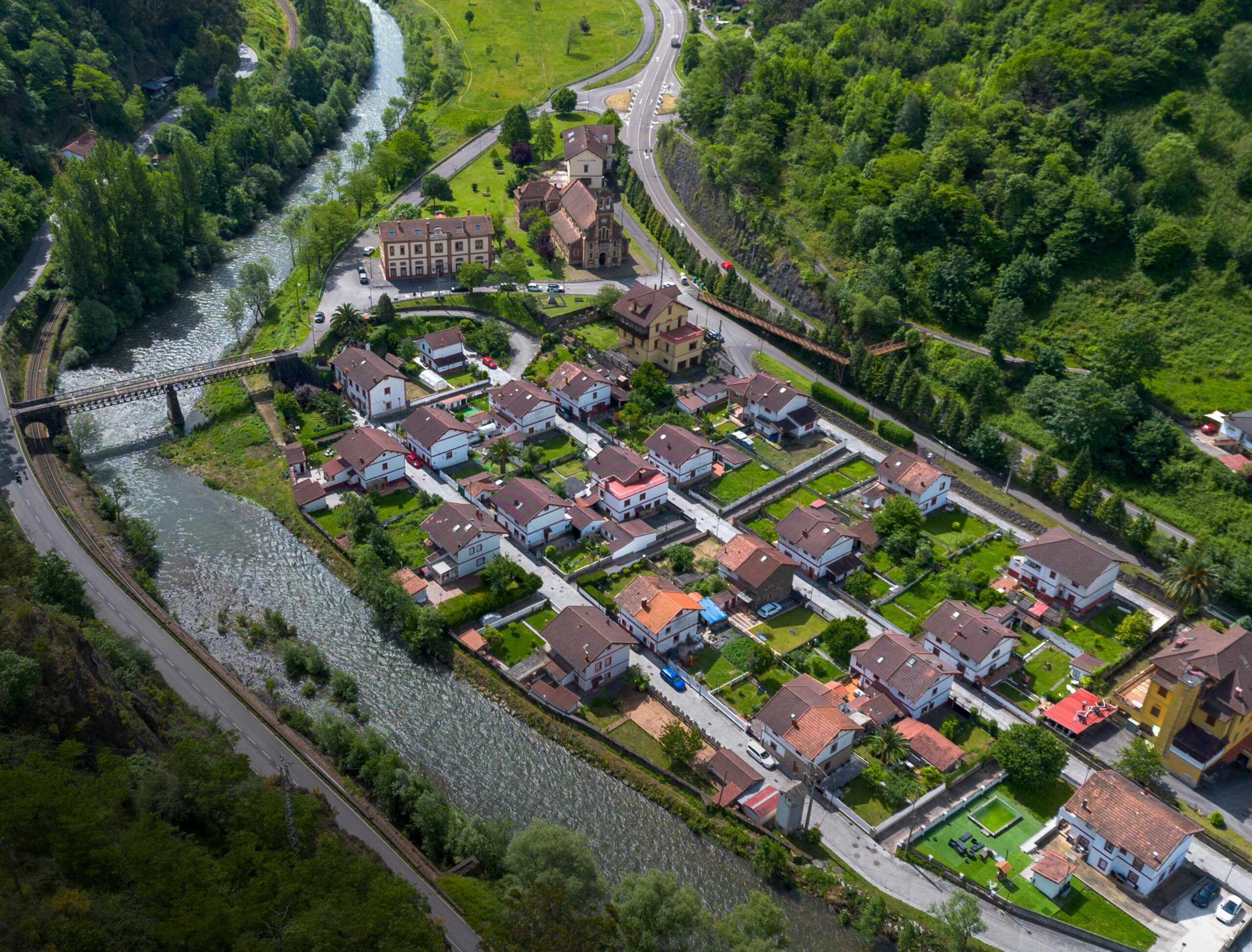 Vista aérea de un pequeño pueblo con casas y un río que lo rodea, rodeado de vegetación