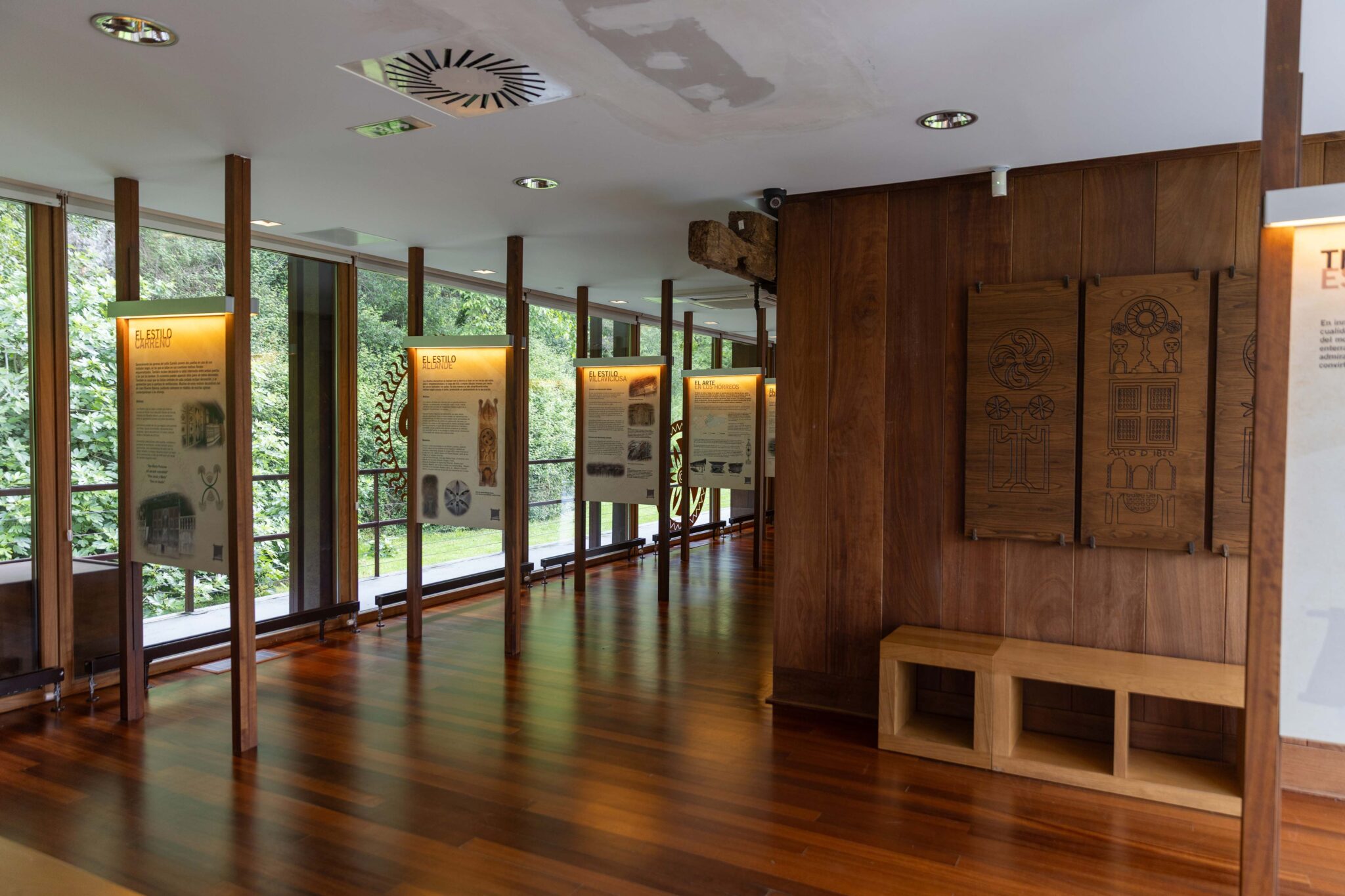 Sala de exhibición con paneles informativos y bancos de madera en un entorno natural