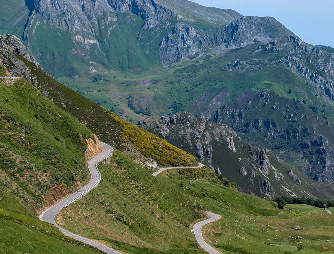Curva de carretera serpenteante en un paisaje montañoso verde y rocoso