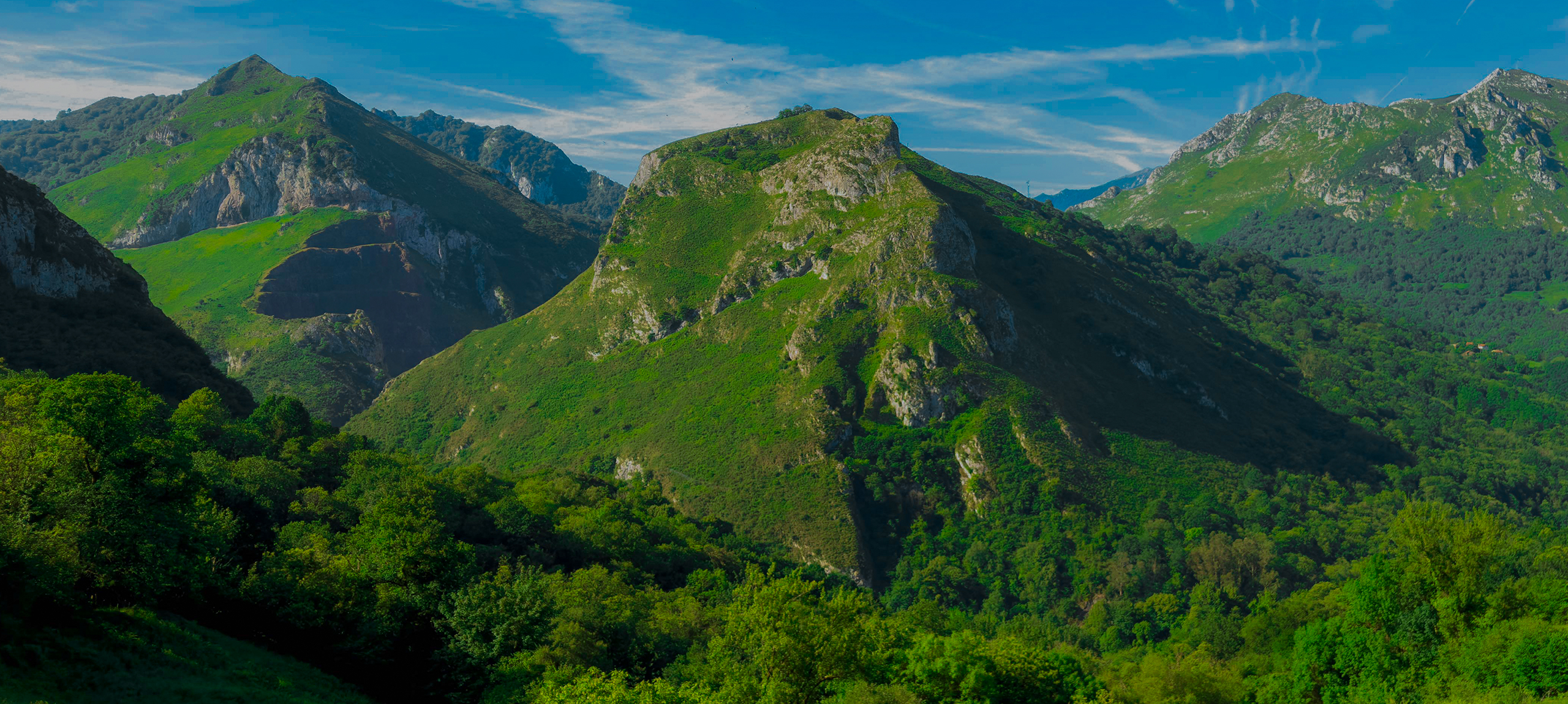 Montañas verdes bajo un cielo azul con nubes dispersas