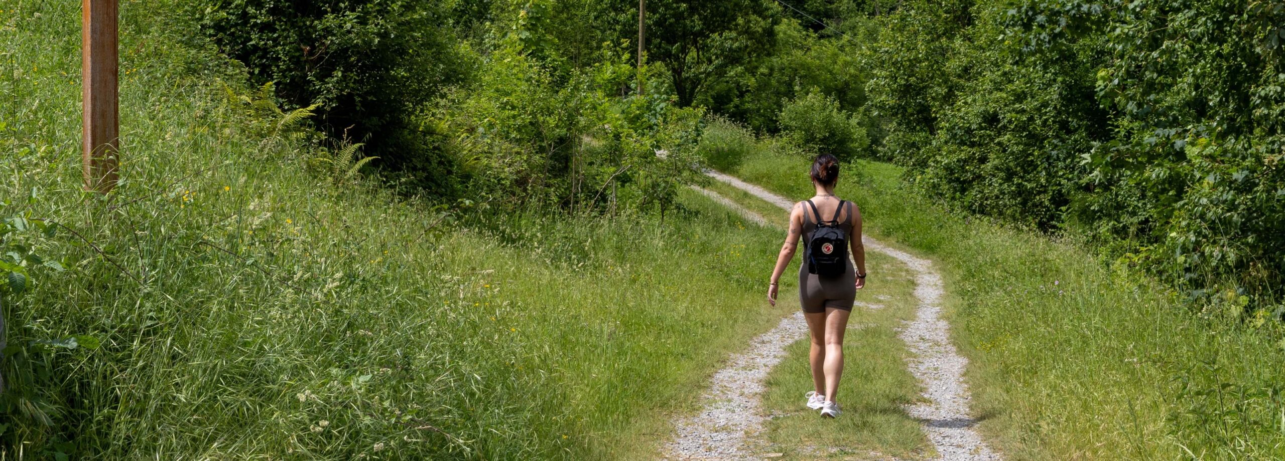 Mujer caminando por un sendero rodeado de vegetación y árboles