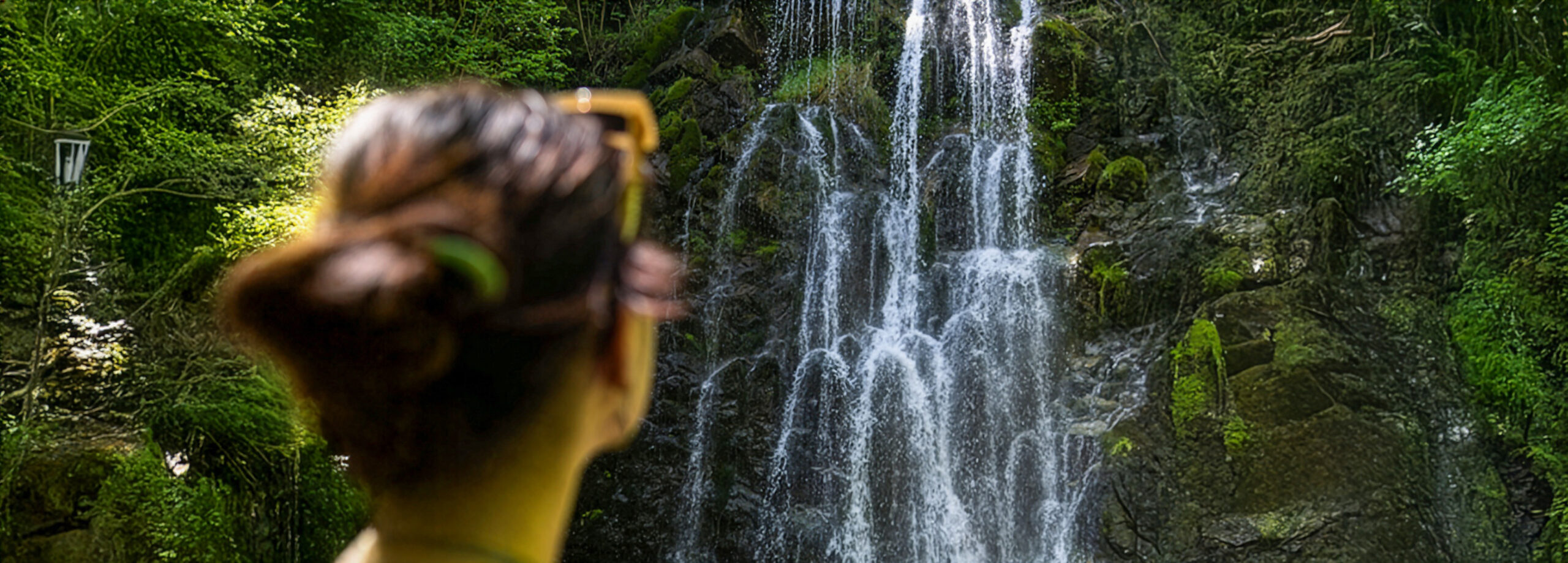 Mujer de espaldas contemplando una cascada en un entorno natural